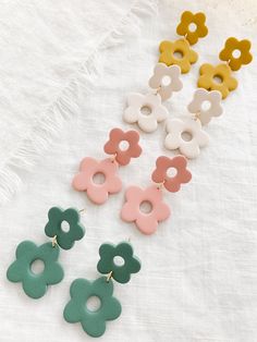 four pairs of flower shaped earrings sitting on top of a white cloth