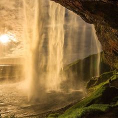 the sun shines brightly in front of a waterfall with water cascading from it