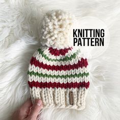 a hand holding a knitted hat on top of white fur