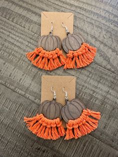 two pairs of orange and brown tasseled earrings on top of a wooden table