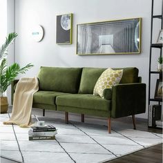 a living room with green couches and pictures on the wall above them, along with bookshelves