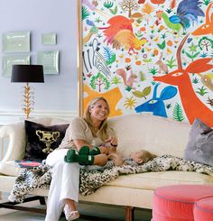 a woman sitting on top of a couch next to a baby in front of a colorful wall