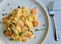 a white plate topped with pasta and shrimp