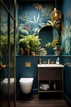 a bathroom with blue walls and green plants on the wall, gold fixtures and white toilet