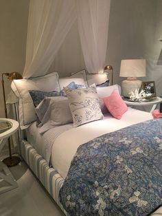 a bed with blue and white comforter next to a table with two lamps on it