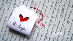 a thank you tag with two hearts attached to it on top of a sheet of paper