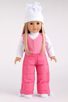 a doll with blonde hair wearing pink overalls and a white knitted hat is standing in front of a white background