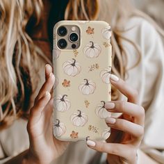 a woman holding up her phone case with pumpkins on it