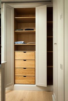 an open closet with wooden drawers and white walls