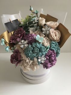 a vase filled with lots of flowers on top of a white table next to a book