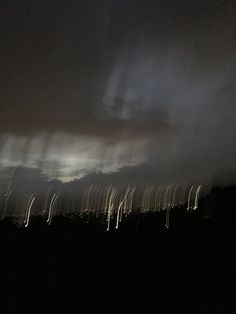 the sky is very dark and there are many light streaks in the clouds above it