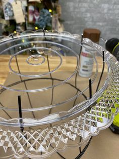 a clear glass cake plate sitting on top of a table next to a bottle of wine