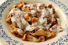 a white plate topped with pasta covered in sauce and cheese on top of blue floraled plates