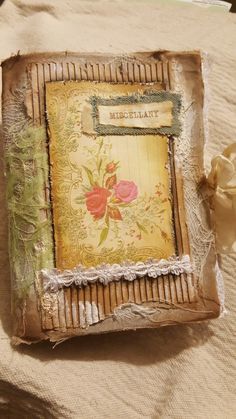 an old photo frame sitting on top of a cloth covered tablecloth with lace and flowers