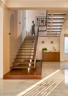 a man walking up the stairs in a house with wood and glass railings on either side