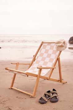 a pair of shoes sitting on top of a beach next to an empty lawn chair