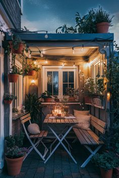 Cozy outdoor patio at night with string lights, potted plants, and a small table set for two with candles. Small Yard Ideas Uk, Cottagecore Patio, Outdoor Spaces Diy, Small Patio Garden Ideas, Apartment Courtyard, Yard Upgrades, Small Patio Ideas Townhouse, Patio Yard Ideas