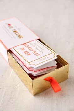 a box with some cards in it sitting on a table next to an orange ribbon