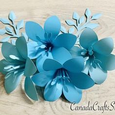 some paper flowers are sitting on a wooden table with the words canada crafts studio written below them