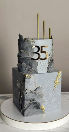 a three tiered cake decorated with gold and silver marbled icing on a white plate