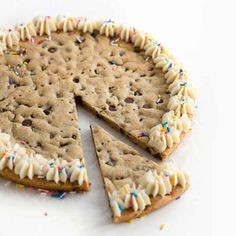 a cookie cake with white frosting and sprinkles cut into four pieces