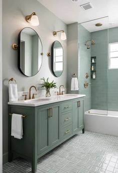 A modern bathroom with Evergreen Fog cabinetry, geometric white floor tiles, black fixtures, and a frameless glass shower.