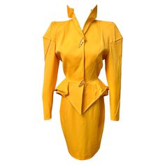 Thierry Mugler vibrant yellow skirt suit set from the Fall Winter 1991 collection. This rare exceptional vibrant yellow skirt suit boasts a stand up collar that is tall and pointed, creating a striking sculptural effect. The accentuated seams on the shoulders add a distinct effect to the jacket's silhouette, emphasizing the marvelous construction, while the cut of the waist flares out with a three dimensional shape. Size: FR36 Condition: This suit was in good condition. There is light wear throu Skirt Suit Set, 1990s Fashion, Yellow Skirt, Chic Leather, Power Suit, Stand Up Collar, Thierry Mugler, A Stand, Suit Set