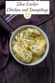 a white bowl filled with chicken and dumplings on top of a wooden table next to a brown towel