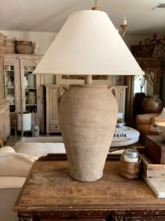 a lamp sitting on top of a wooden table next to a white shade over it