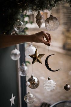 a person is holding an ornament in front of a christmas tree with ornaments hanging from it