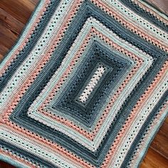 a crocheted blanket is laying on a wooden floor