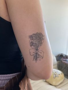 a woman with a tattoo on her arm holding a bouquet of flowers in her hand