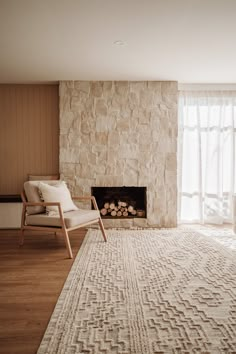 a living room with a fireplace, chair and rug in front of the fire place