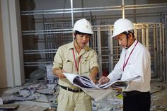 two men in hard hats looking at blueprints