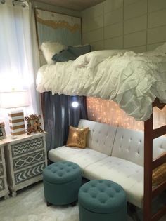 a loft bed with a couch underneath it and two stools in front of it