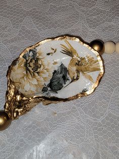 a gold and white decorative object on a lace tablecloth with bead necklaces