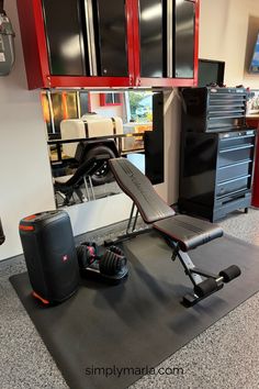 a gym equipment set up in the middle of a room with red cabinets and drawers