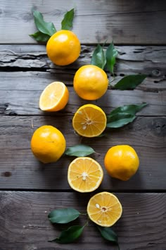 several oranges with leaves on a wooden table