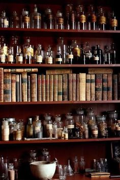 an old book shelf filled with lots of different types of books and jars on top of wooden shelves