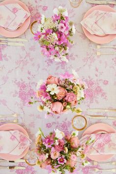 the table is set with pink flowers and gold place settings for an elegant dinner party