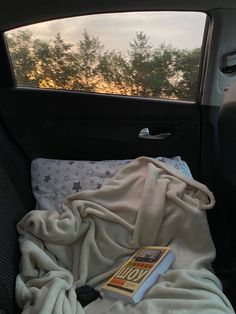 the back seat of a car with a blanket on it and a book in the backseat