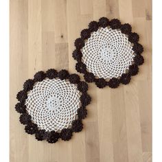 two black and white crocheted doilys sitting on top of a wooden floor