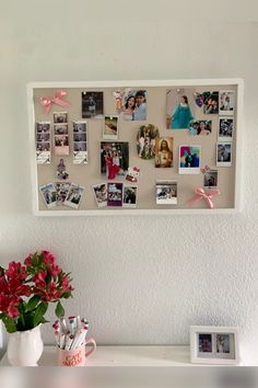 a white shelf topped with pictures and flowers next to a vase filled with red flowers