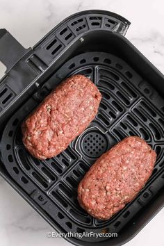 two hamburger patties cooking in an air fryer