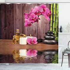 a shower curtain with pink orchids and rocks in front of it on a wooden floor