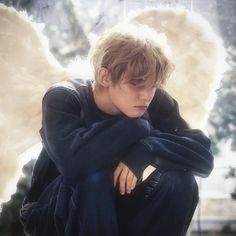 a young man with angel wings sitting on the ground