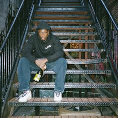 a man sitting on top of a set of stairs with a bottle in his hand