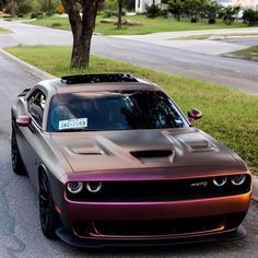 a purple and black car parked on the side of a road next to a tree