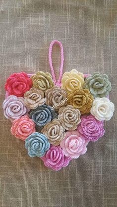 a heart shaped ornament made out of crochet yarn and felt flowers