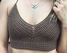 a woman wearing a brown crochet top holding a cell phone